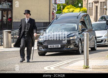 Alloa, Großbritannien. Juni 2020. Der Bestattungsdirektor geht vor dem Leichenwagen, der den Leichnam Norman Alexanders durch die Straßen trägt.die Bewohner von Alloa kamen heraus, um einem Einheimischen Norman Alexander, der am 5. Juni 2020 im Alter von 90 Jahren verstorben ist, ihre Ehre zu erweisen. Norman war ursprünglich aus Aberdeenshire, kam aber nach Alloa, um als CO-OP zu arbeiten, bevor er Eisenhund wurde, tat er viel für die lokale Gegend. Sein Sarg wurde um Alloa herum bereist, bevor er zum Falkirk Krematorium gebracht wurde. Kredit: SOPA Images Limited/Alamy Live Nachrichten Stockfoto