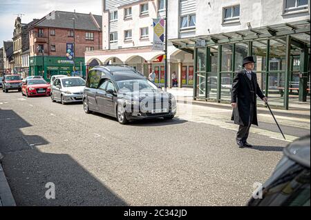 Alloa, Großbritannien. Juni 2020. Der Bestattungsdirektor geht vor dem Leichenwagen, der den Leichnam Norman Alexanders durch die Straßen trägt.die Bewohner von Alloa kamen heraus, um einem Einheimischen Norman Alexander, der am 5. Juni 2020 im Alter von 90 Jahren verstorben ist, ihre Ehre zu erweisen. Norman war ursprünglich aus Aberdeenshire, kam aber nach Alloa, um als CO-OP zu arbeiten, bevor er Eisenhund wurde, tat er viel für die lokale Gegend. Sein Sarg wurde um Alloa herum bereist, bevor er zum Falkirk Krematorium gebracht wurde. Kredit: SOPA Images Limited/Alamy Live Nachrichten Stockfoto