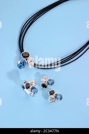 Schmuck-Set Tricolor mit Halskettenring und Ohrringen auf blauem Hintergrund Stockfoto