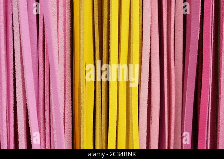 Ausschnitt Textur closeup auf mehrere Rosa und Gelb bunte Lederbändern. Stockfoto