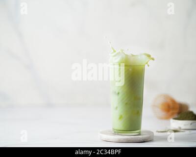 Hausgemachte Eistee Matcha Latte mit Spritzer auf weißem Hintergrund. Kopieren Sie Platz für Text oder Design Stockfoto