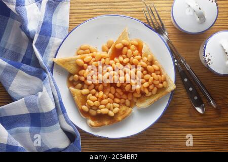 Gebackene Bohnen auf Toast auf einem hölzernen Hintergrund Stockfoto