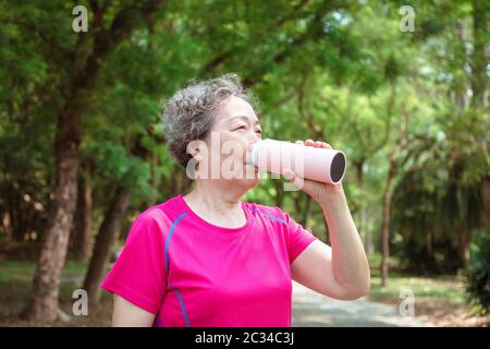 asiatische Seniorin trinkt nach der Übung Wasser Stockfoto