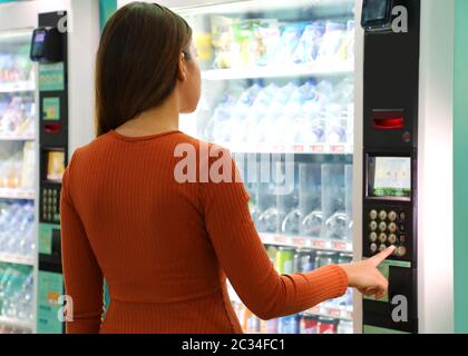 Junge reisende Frau wählen Sie einen Snack oder ein Getränk am Automaten im Flughafen. Automaten mit Mädchen. Stockfoto