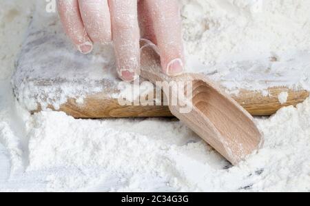 Ein einfacher Holzlöffel mit Weizenmehl beim Kochen, auf einem Küchentisch auf dem Land Stockfoto