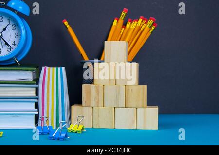 Die Kugel und die Uhr stehen auf einem Stapel Bücher, neben einem Glas Bleistifte und die Pyramide ist mit Holzwürfeln gefaltet. Stockfoto