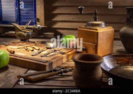 Rustikale Holz Vintage Kaffeemühle. Vintage Stillleben mit antiken Gerichten und grünen Äpfeln. Vintage Stillleben mit Utensilien und einer Kaffeemühle o Stockfoto