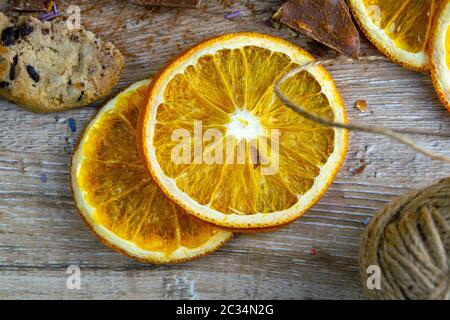 Getrocknete Orangen, Schokoladenscheiben, Schokoladenkekse und Zimt auf einem Holztisch. Stockfoto