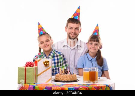 Glücklicher Vater und zwei Töchter am Festtisch zu Ehren des Geburtstags Stockfoto