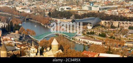 Schöne Aussicht auf den Fluss Kura und die Brücke des Friedens in Tiflis. Brücke ist eine bogenförmige Fußgängerbrücke in Tiflis Stockfoto