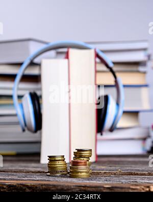 Buch mit Kopfhörer vor Stapel von verschiedenen Büchern auf Holztisch Stockfoto