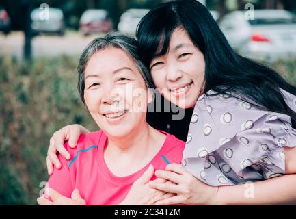 Asiatische ältere Mutter und ihre erwachsene Tochter sind umarmen Stockfoto