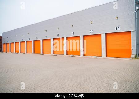 außen eine gewerbliche Lagerhalle mit orange Rolltore Stockfoto
