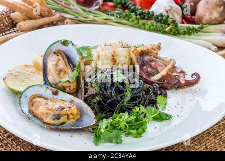 Schwarze Spaghetti Alle Vongole. Schwarze Meeresfrüchte-Pasta mit Muscheln und Joghurt Knoblauchsauce über schwarzem Tisch. Mediterrane Delikatesse, Meeresfrüchte schwarze Pasta mit Stockfoto