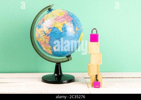 Globus und Holzwürfel in Form eines Hauses, zusammen mit einem rosa Pad und Schlüssel ausgekleidet. Das Konzept der Vermietung eines Hauses. Stockfoto