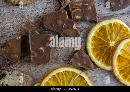 Getrocknete Orangen, Schokoladenscheiben, Schokoladenkekse und Zimt auf einem Holztisch. Stockfoto