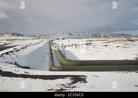 Pipelines in Island, Geothermie-Wärmetransport auf vulkanischem Gelände, Schnee auf dem kargen Land Stockfoto