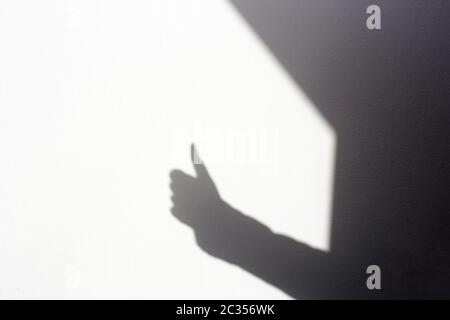 Silhouette Schattenhand, die an der weißen Wand nach oben tummelt, isoliert im Zuhause für Text Stockfoto