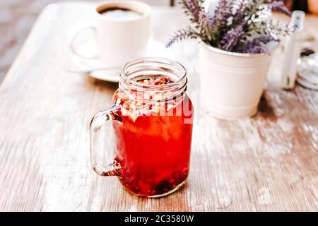 Tisane oder roter Kräutertee in einem transparenten Glas auf einem Tisch im Freien in einem Teehaus auf der Straße Stockfoto