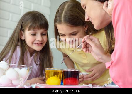 Familienspaß dabei zu beobachten, wie die Eier in einer Lösung mit Farbstoffen bemalt werden Stockfoto