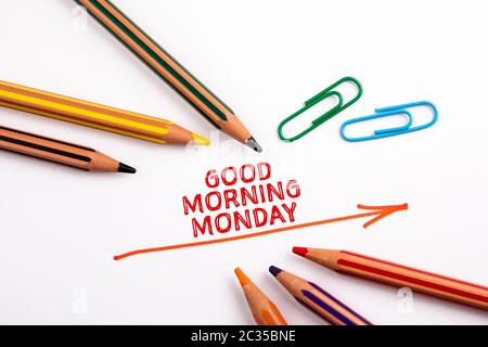 GUTEN MORGEN MONTAG. Roter Richtungspfeil und Buntstifte auf weißem Hintergrund Stockfoto
