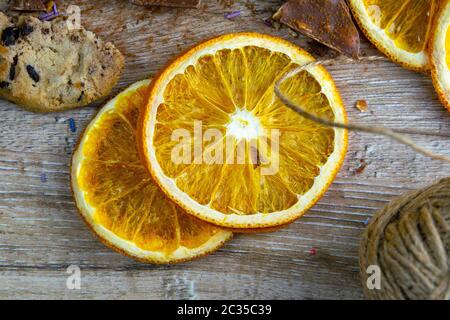 Getrocknete Orangen, Schokoladenscheiben, Schokoladenkekse und Zimt auf einem Holztisch. Stockfoto