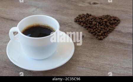 Kaffee zubereiten. Tasse duftenden Kaffee. Bohnen sind in Form eines Herzens ausgelegt. Stockfoto