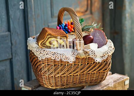 Traditionelle österliche Küche mit Schinken, Eiern und Brot. Urlaub im Freien. Der Osterkorb ist mit allerlei köstlichen Delikatessen gefüllt Stockfoto