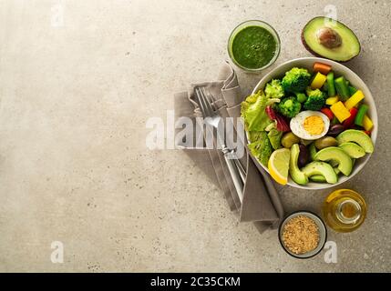 Gesundes Salatessen mit Ei, Avocado und gemischtem frischem Gemüse auf grauem Hintergrund Draufsicht. Lebensmittel und Gesundheit. Gesundes Essenskonzept Stockfoto