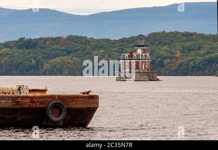 Eine rostige alte Barge sitzt im Vordergrund in der Nähe des Hudson Athen Leuchtturm in Upstate New York USA Stockfoto