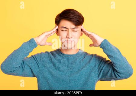 asiatischer junger Mann mit Kopfschmerzen Stockfoto