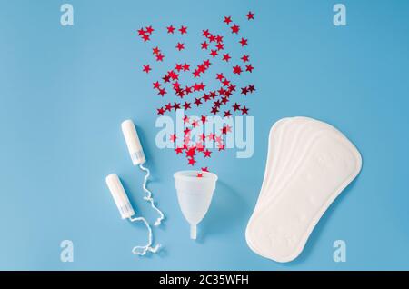 Feminines Sanitärpolster, Menstruationsbecher und Tampons auf blauem Hintergrund. Konzept der weiblichen Hygiene während der Menstruation. Konzept kritischer Tage. Flach l Stockfoto