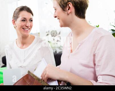 Porträt von zwei glücklichen Frau sitzen zusammen einander anguckend Stockfoto