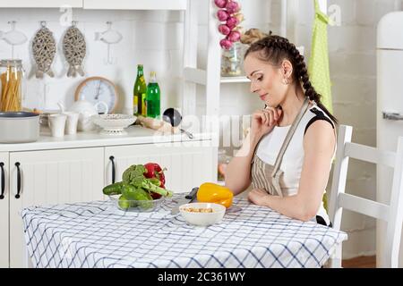 Junge Frau in einer Schürze kocht gesundes Essen in der Küche. Stockfoto