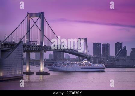Venus Kreuzfahrt Schiff segeln in Odaiba Bucht unter der Rainbow Bridge in einem rosafarbenen Sonnenuntergang Licht. Stockfoto