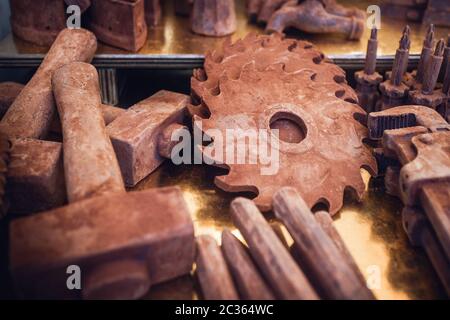 Gefälschte Werkzeuge wie Hammer, Schraubendreher und Kreissägeblatt mit Schokolade auf dem Marktstand eines italienischen Schokoladenereignisses im Piemont Stockfoto