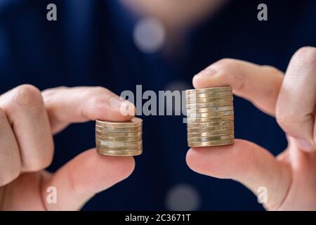 Mann mit zwei Münzen Stapeln zu vergleichen. Stockfoto