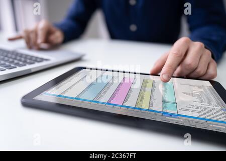 Ansicht der Geschäftsmann Hand Analyse der Daten über digitale Tablet über Schreibtisch Stockfoto