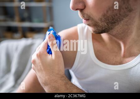 Nahaufnahme eines Mannes Anwendung Cool Gel Pack auf seiner Schulter Stockfoto