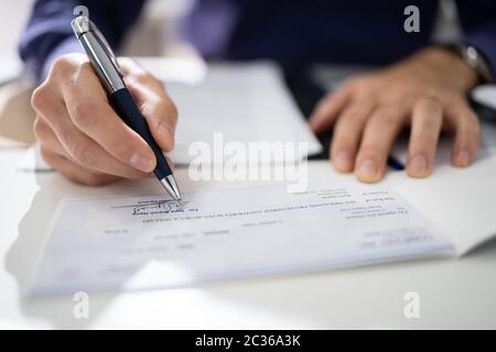 Nahaufnahme von Menschenhand schreiben auf Scheck Stockfoto