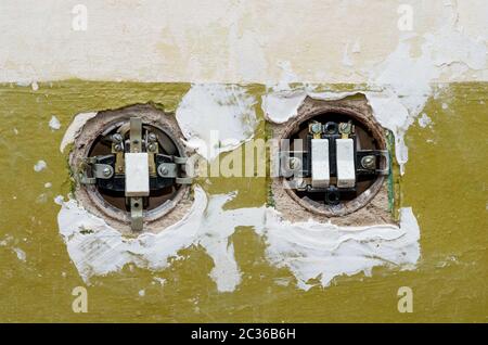 Zwei alte elektrische Schalter in der Wand montiert. Die Abdeckungen der Schalter sind geöffnet. Stockfoto