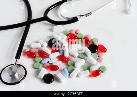 Haufen von bunten Medizin Pillen auf weißem Hintergrund mit Arzt Stethoskop. Pharmakonzept. Stockfoto