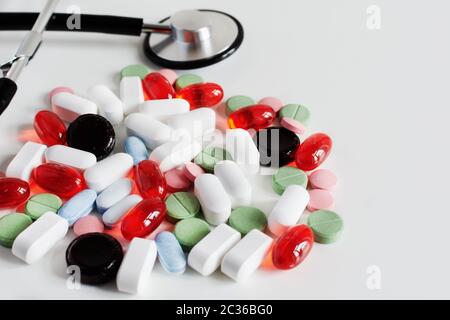 Haufen von bunten Medizin Pillen auf weißem Hintergrund mit Arzt Stethoskop. Pharmakonzept. Stockfoto