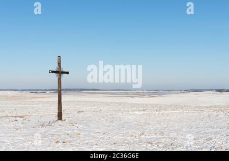 alten verwitterten hölzernen katholische überqueren auf einer schneebedeckten Wiese Stockfoto