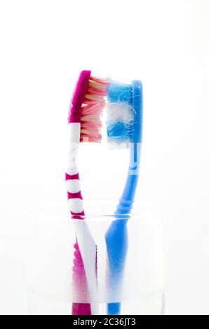 zwei alte verwendet bunte Zahnbürsten in einem Glas Stockfoto