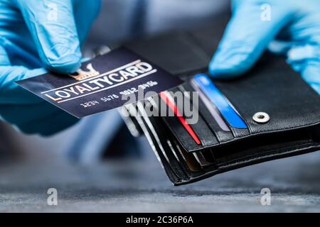 Kunden, Die Treuekarte Von Wallet In Handschuhen Nehmen, Um Sich Vor Coronavirus Zu Schützen Stockfoto