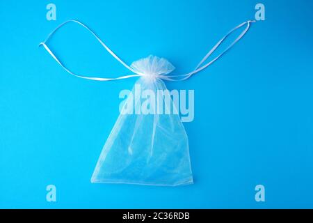 Tasche aus weißem, transparentem Synthetikmaterial für Geschenke und Kosmetik auf blauem Hintergrund, Draufsicht Stockfoto
