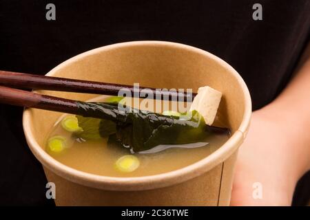 Frau essen Miso Suppe im Takeaway Cup. Der traditionellen asiatischen Küche. Stockfoto