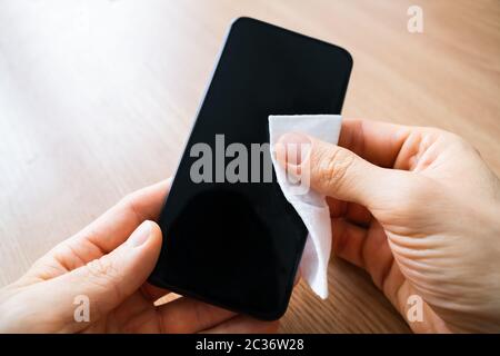 Man Wischt Den Bildschirm Des Mobiltelefons Mit Desinfektionsmittel Ab Stockfoto