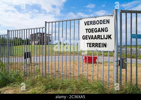 Kein Umbruch, gefährlicher Bereich (verboden toegang, gevaarlijk terrein in niederländischer Sprache) an einem Metallzaun vor einer Ruine einer alten Fabrik Stockfoto